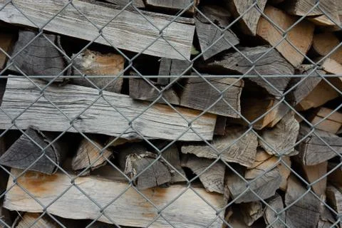 Fire wood stack piled up behind fence Stock Photos