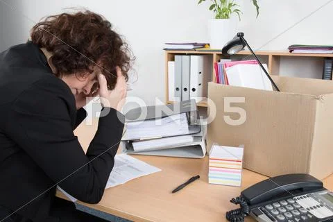 Fired employee holding her head in desperation with her box Stock Photos