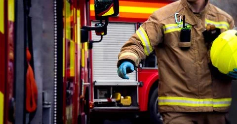 Firefighter in action with hand reaching for fire truck door Photos