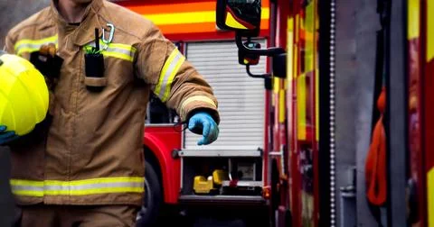 Firefighter in action with hand reaching for fire truck door Фото