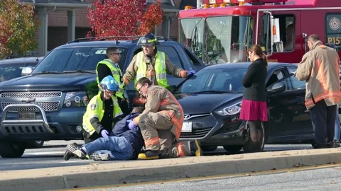 Firefighter and paramedic helping black hurt man into seated position at 動画素材 145984422