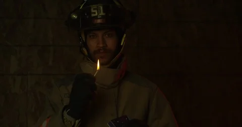 Firefighter blows out lit match while looking into camera - slow motion Stock Footage 107002797