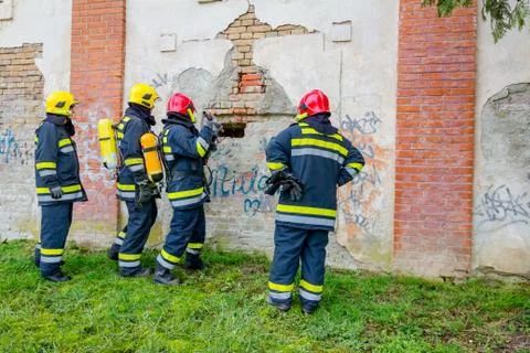 Firefighter is breaking through wall, estimating current situation Stock Photos