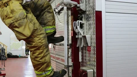 Firefighter climbing fire engine in fire station Stock Footage 220205249