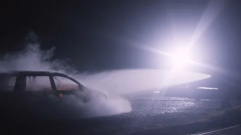 Firefighter combating fire on a burned car accident at night with water hose Stock-Footage 230029852