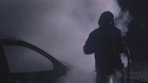 Firefighter combating a fire. Fireman putting out a burning car on flames with Vídeos de archivo 220485184