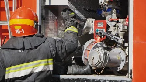 Firefighter connecting a hose to the fire engine pump system during an Stock Photos