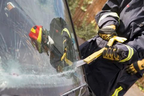 Firefighter cutting out a windshield after an accident Stock Photos