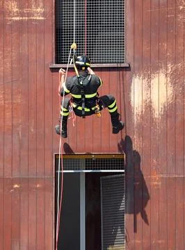 Firefighter descending from a building using the double rope technique duri.. Fotos de archivo