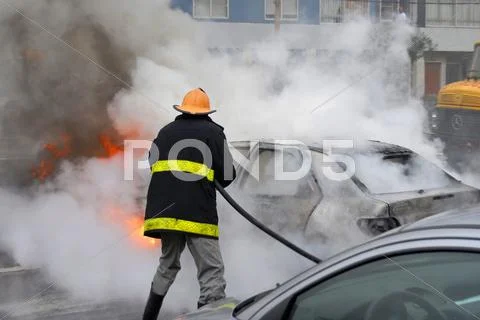 Firefighter extinguishing a car fire. last stage of a fire Stock Photos
