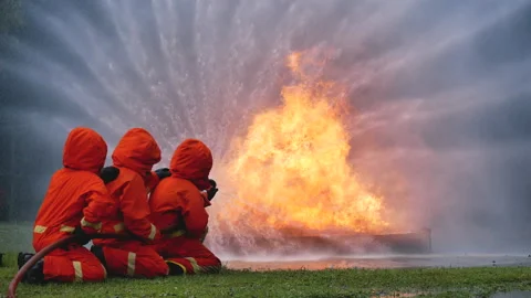 Firefighter fighting with flame using fire hose chemical water foam spray engine Video stock 148543599