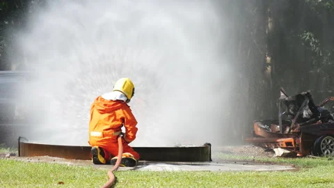 Firefighter fighting with flame using fire hose chemical water foam spray engine Stock-Footage 154355292
