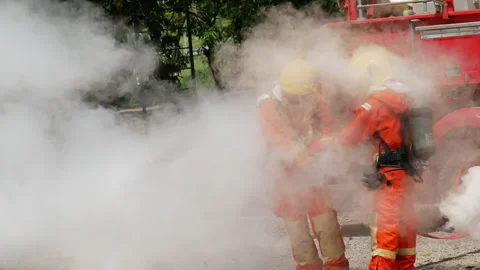 Firefighter fighting with flame using fire hose chemical water foam spray 動画素材 337748372