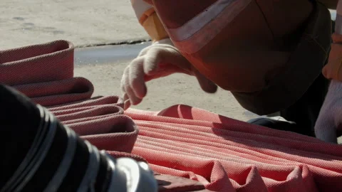Firefighter folding red fire hose during training Stock Footage 321408770