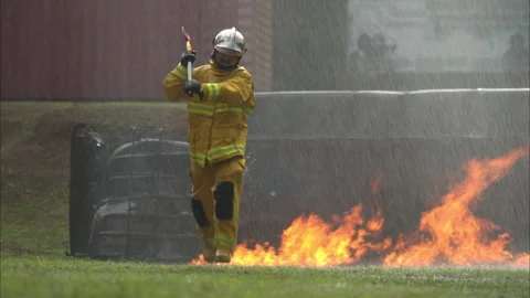 A firefighter in full protective gear runs through intense flames Vídeos de archivo 326217294