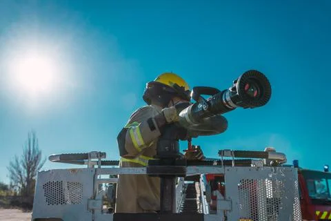 Firefighter on ladder next to lance to launch pressurized water. Stock Photos