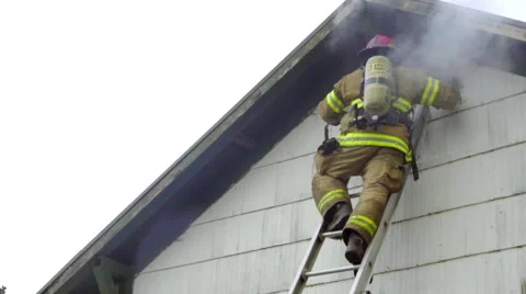 Firefighter looks inside a burning attic Stock Footage 60794259
