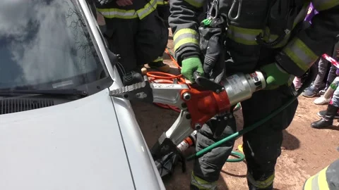 Firefighter opens door of car after accident with huge pneumatic plyers Stockbeeldmateriaal 135361808