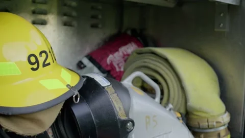 A firefighter opens up the red panel on a firetruck to reveal fire saving Vidéo 309518279