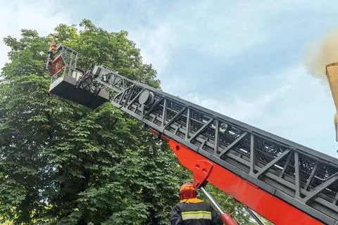 Firefighter operating hydraulic rescue platform ladder extended high in the.. 스톡 사진