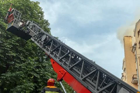 Firefighter operating hydraulic rescue platform ladder extended high in the.. 스톡 사진