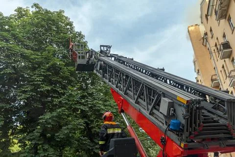 Firefighter operating hydraulic rescue platform ladder extended high in the.. 스톡 사진