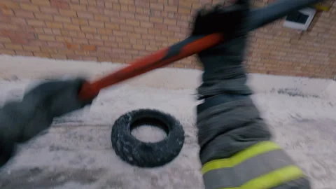 A firefighter practices hitting a tire with a sledgehammer with his right hand. Stock Footage 321858637