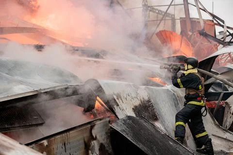 A firefighter puts out a burning warehouse. Stock Photos