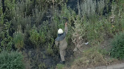 Firefighter puts out fire. Fireman finds fire in dried grass and goes to stew it Stock Footage 64944523