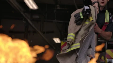 Firefighter putting on his uniform in front of blaze Stock Footage 299161491