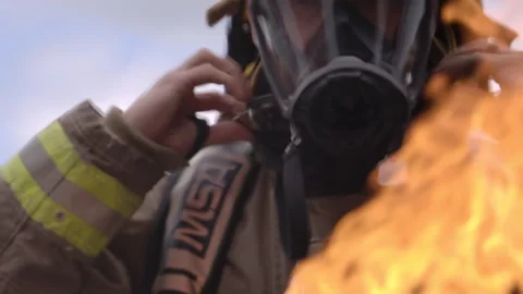 Firefighter putting on mask in front of flames Stock Footage 299163765