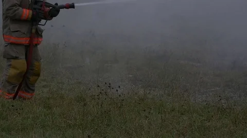 Firefighter putting out fire in farmers field Stock Footage