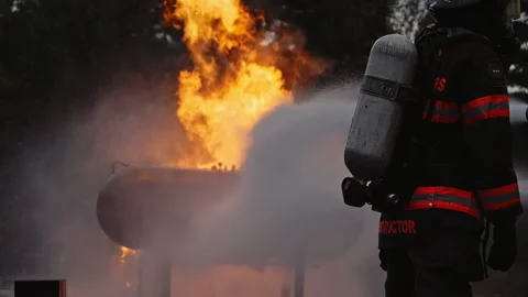 Firefighter putting out roaring fire with hose - dramatics - high contrast Stock Footage 168460726