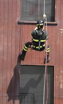 Firefighter is rappelling down the building in full uniform and helmet Fotos de archivo