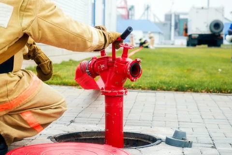 Firefighter sits next to fire hydrant. Back view. Firemen training Stock Photos