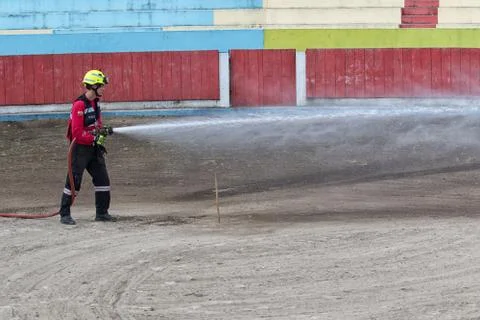 Firefighter is soaking the soil of the bullfighting ring in Ecuador Stock Photos