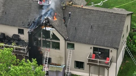 Firefighter spraying water with hose on burning house. Aerial top down. Windy Stock Footage 313996367