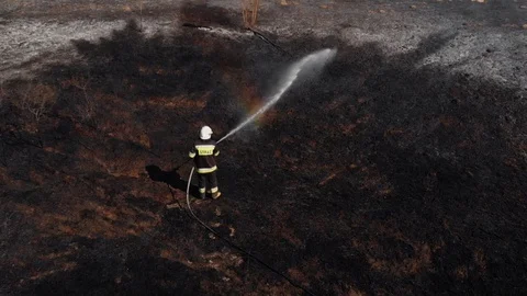 Firefighter standing in the middle of a wildfire site seen from above, all Stock Footage 108683166