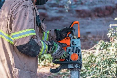 Firefighter starting chainsaw, in rescue. Stock Photos