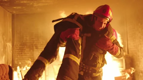 Firefighter taking unconscious firefighter out of a burning house Stock Footage 283143444