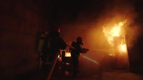Firefighter trying to extinguish fire in a burning house Stock Footage 283142991