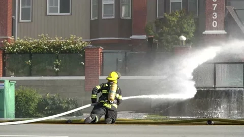 Firefighter trying to put out a fire at a residential building. Stock Footage 135435123