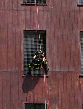 Firefighter in uniform rappelling down building during fire station trainin.. Fotos de archivo