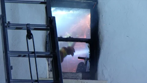 Firefighter uses axe to break through burning wall 스톡 동영상 97582046