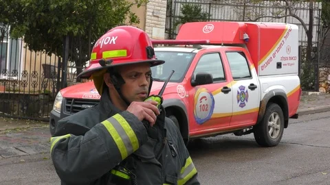 A firefighter using walkie talkie in front of a fire truck Stock Footage 106693474