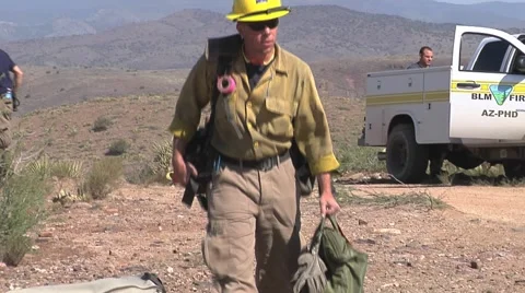 Firefighter walks up to helicopter to load pack on mountain top Stock Footage 40951202