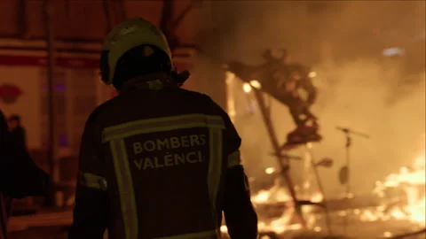 Firefighter watching falla burning during Las Fallas crema at night Stock Footage 336785531