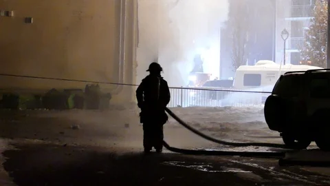 Firefighter working on building fire in low light Stock Footage 125230800