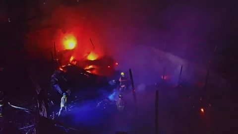 Firefighters battling a large building fire at night. Aerial view Stock Footage 331788412