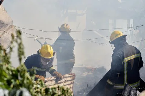 Firefighters braking apart rusty burned sheet mettle Stock Photos